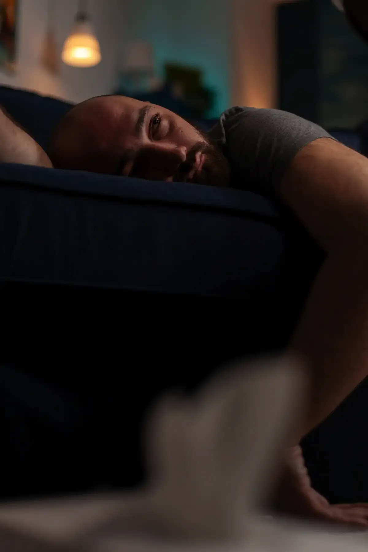 Man lying on couch in deep sorrow, symbolizing emotional exhaustion and questioning God's presence in suffering